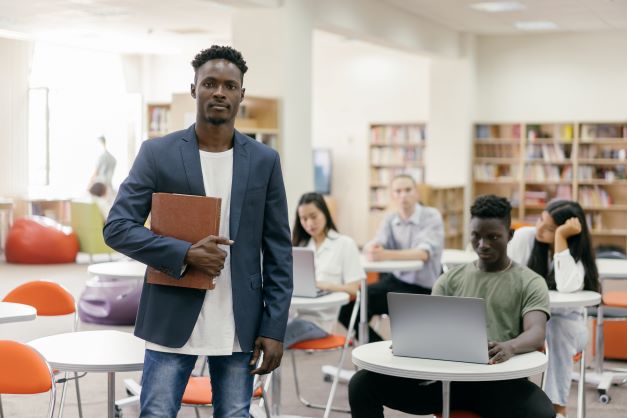 male teacher standing in classroom with students in the background