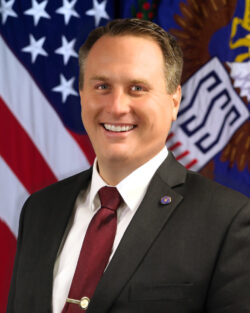 Acting Director Joel Spangenberg pictured in front of flags