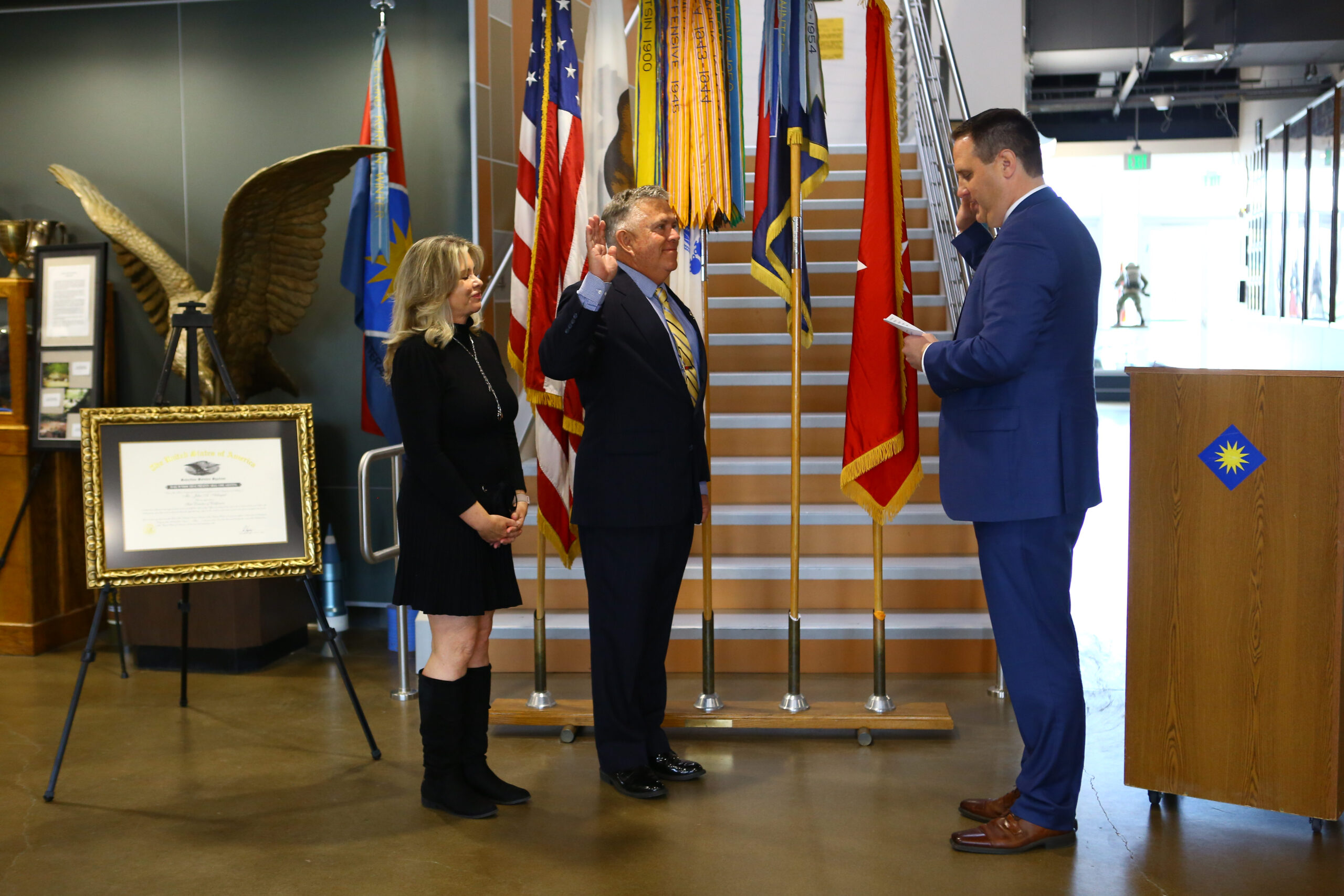 Selective Service System Acting Director Joel C. Spangenberg, right, administers the oath of office to John A. Arbogast, center, the system’s new state director for California, as Arbogast’s wife, Nancie, looks on during a ceremony,